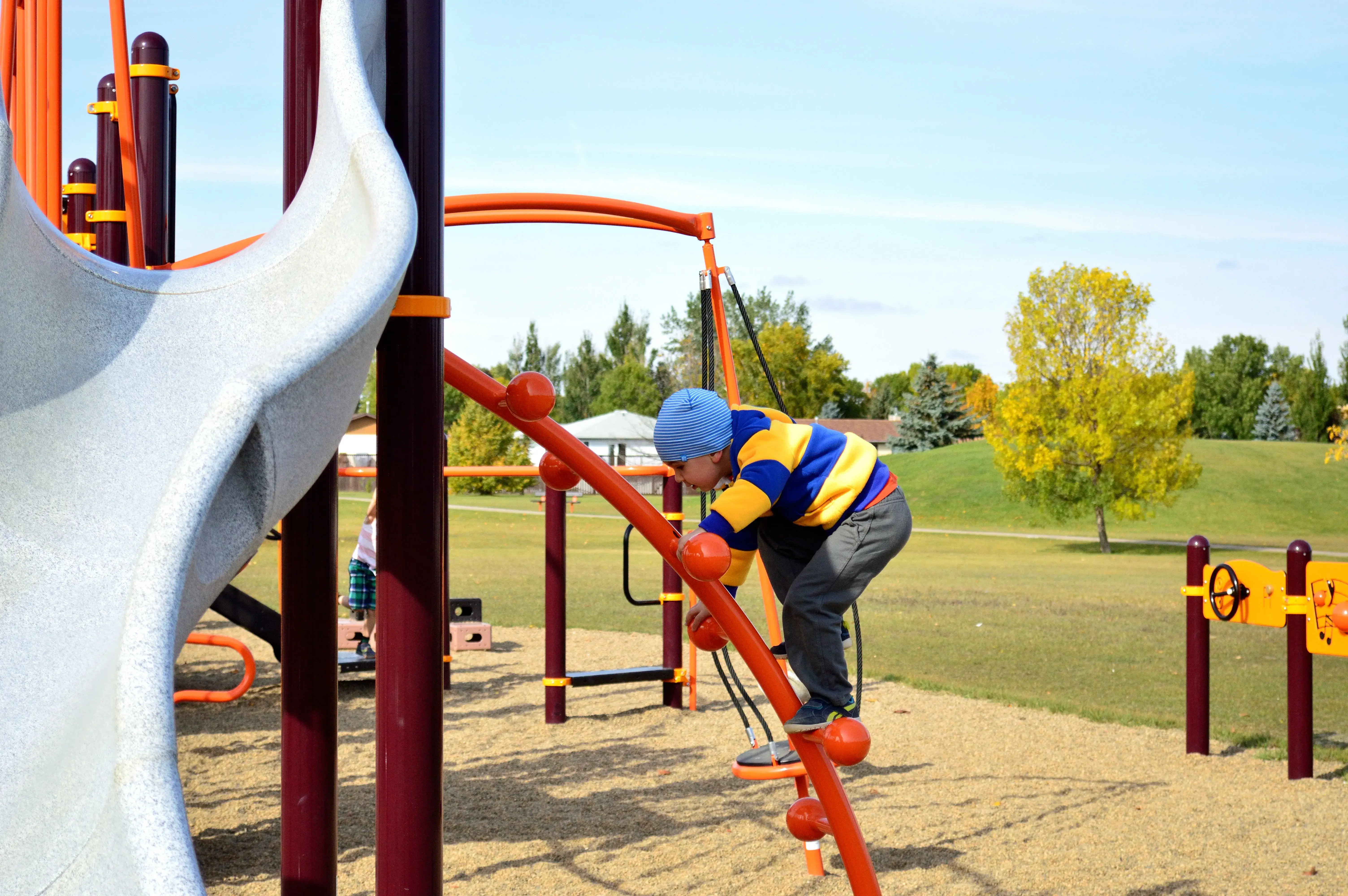 A boy is climbing a play structure in the Parkdale Park in Brandon, MB